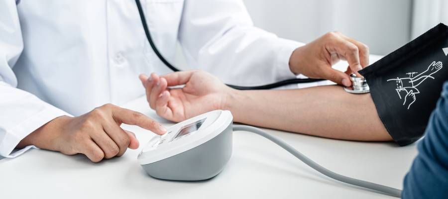 Bir doktorun bir hastanın tansiyonunu dijital bir cihazla ölçmesi.