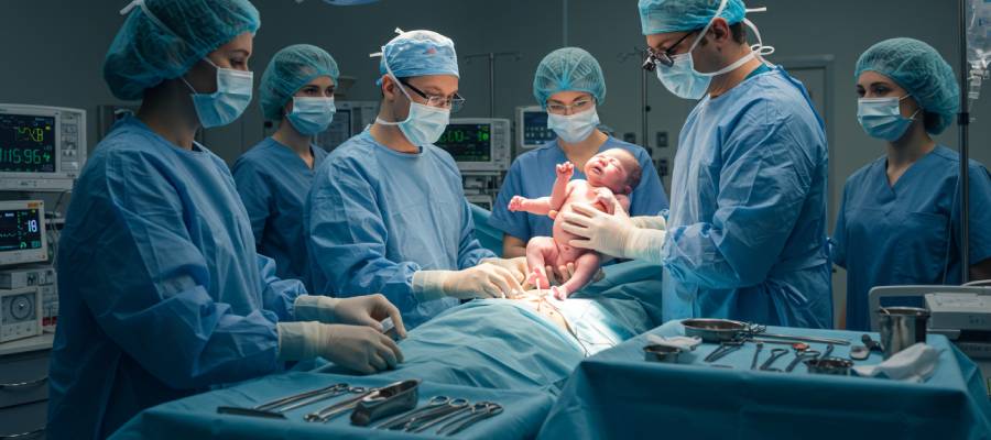 Bir ameliyathane ortamında gerçekleştirilen sezaryen doğumda, sağlık personeli yeni doğan bir bebeği karşılıyor.