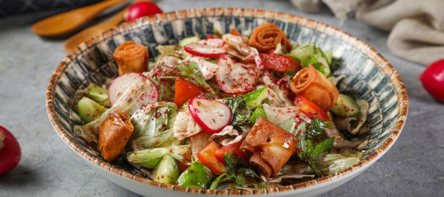 İçerisinde marul, domates, salatalık, turp ve kızarmış pide parçaları bulunan, üzerine bolca sumak serpilmiş, iştah açıcı bir salata.