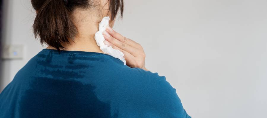 Boyun bölgesine havlu tutan ve sırt kısmı terlemiş olan bir kişi, aşırı terleme (hiperhidroz) sorunu yaşıyor.