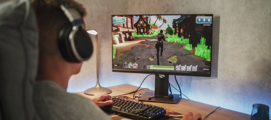 Kulaklık takmış genç bir birey, karanlık bir odada bilgisayar başında yoğun şekilde video oyunu oynuyor. Ekranda renkli grafiklerle tasarlanmış bir açık dünya oyunu görülüyor. Görsel, oyun bağımlılığının bireyin dikkatini tamamen ekrana odakladığı anlardan birini temsil ediyor.