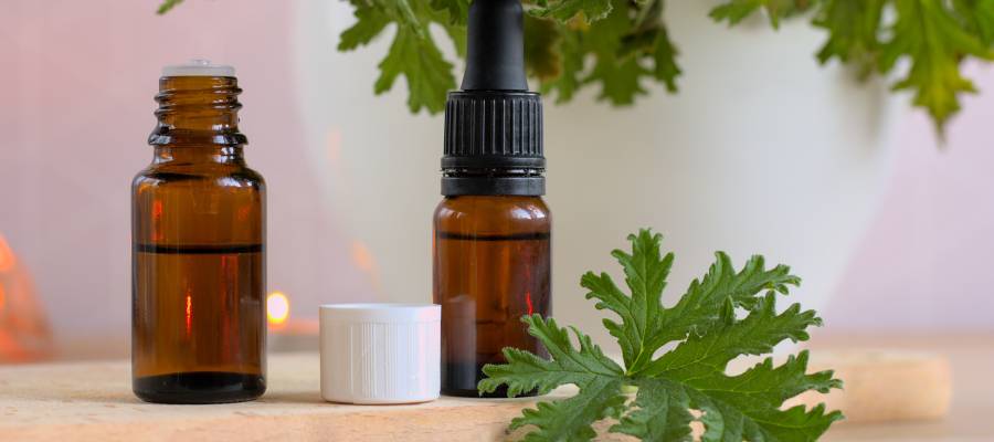 Citronella bitkisi yaprağı ve uçucu yağı ile birlikte doğal sivrisinek kovucu olarak kullanılan şişeler, ahşap yüzey üzerinde sergileniyor.